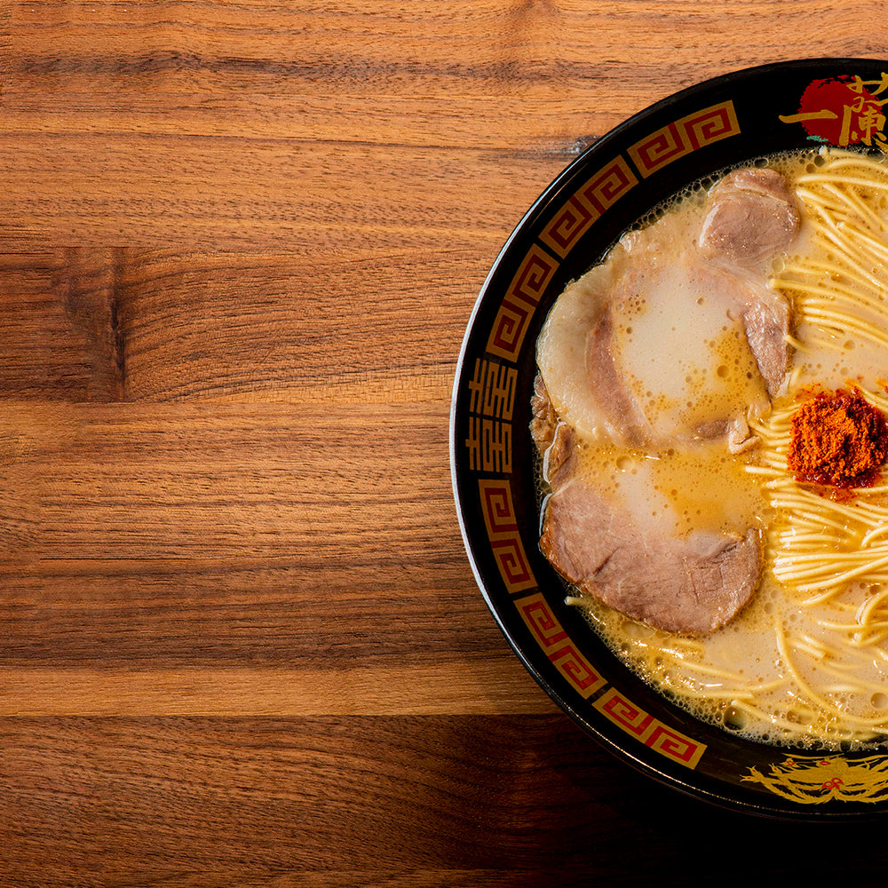 Wooden table with a bowl of ICHIRAN's Classic Tonkotsu Ramen on the right